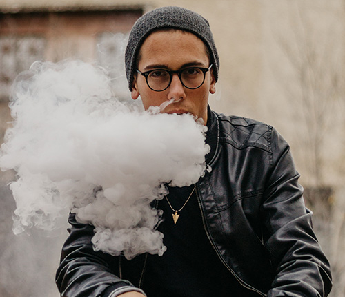 man vaping wearing black jacket shows how vaping causes tooth decay symbolically