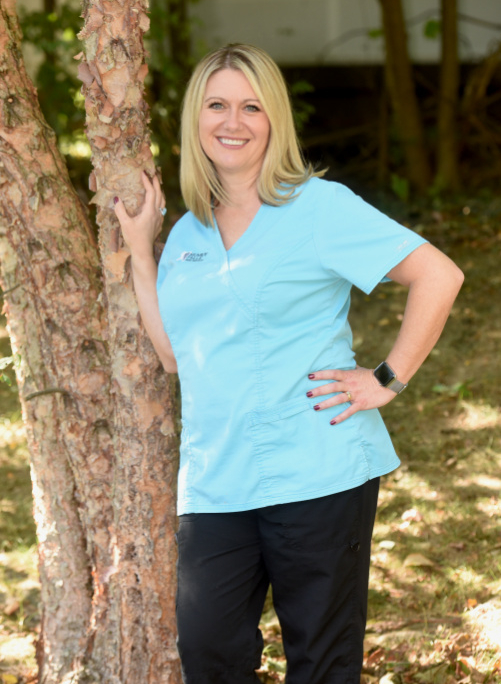Mica Bartels DMD practices family and cosmetic surgery near Tallmadge poses outside in blue MFFD shirt